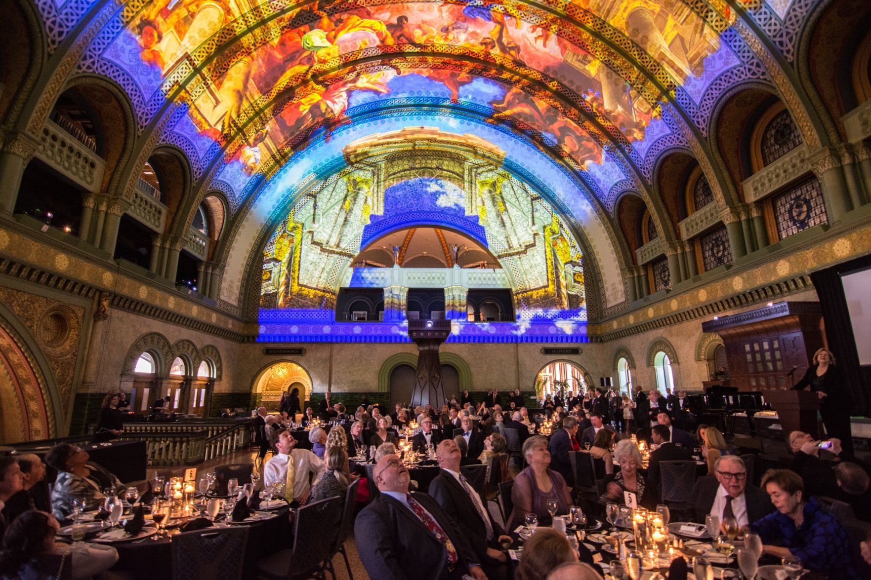 Guests look up at the light show on the ceiling of the grand hall in Union Station